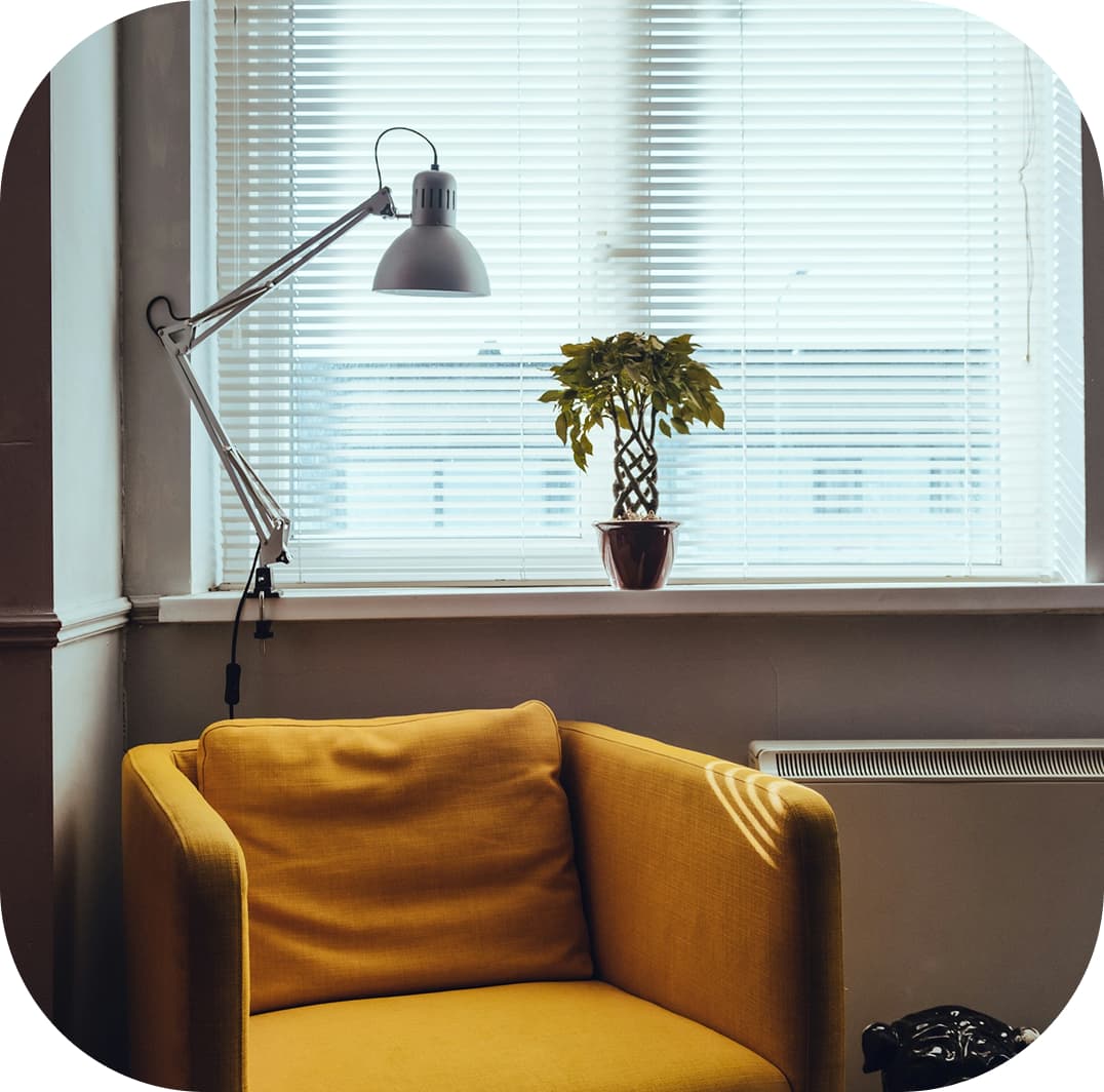Image of an armchair next to the window with curtains